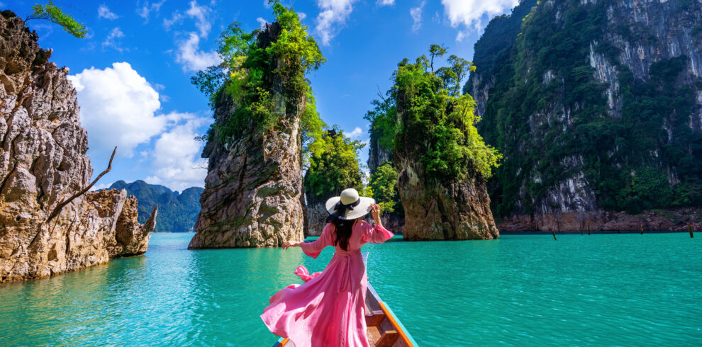 Beautiful girl standing on the boat and looking to mountains in